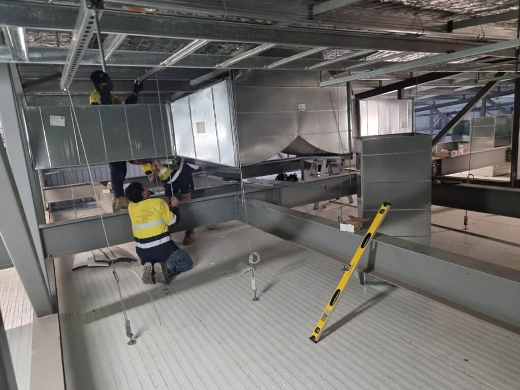 Insulation workers installing insulation ducts on ceiling